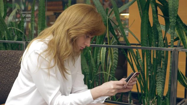 Woman talking on cellphone and drinking Coffee in cafe. 4k