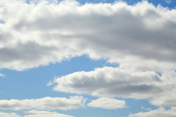 Small cumulus clouds are lit by the sun. The sun is not visible. Light coloured.