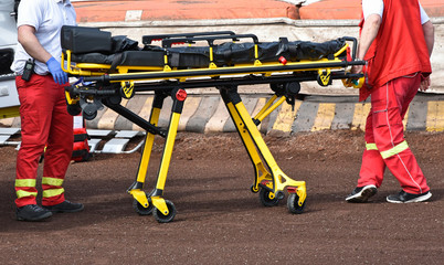 Ambulance staff with a stretcher on a sport track