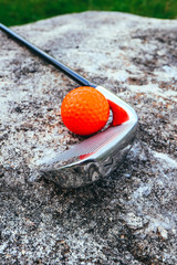 Golf stick and a red bright ball on a golf course, close up. Luxury sport concept.