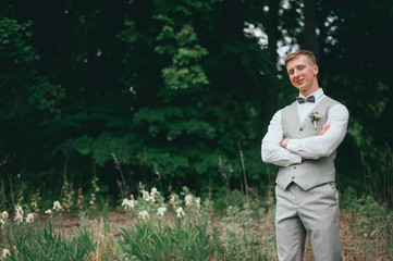 A handsome groom looks happy on his wedding day in grey and yellow.