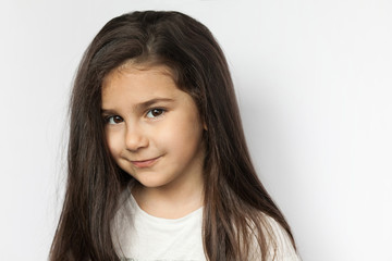 Fototapeta premium Portrait of happy smiling brunette child girl with long hear isolated on white background. Place for text.