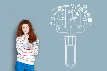 Thoughtful scientist. Experienced clever scientist thoughtfully looking into the distance while standing with a book in her hands