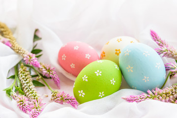 Fototapeta na wymiar Happy easter! Colorful of Easter eggs in nest with flower, paper star and Feather on white cheesecloth background.
