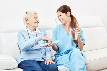 Seniorin erhält ein Medikament von Pflegedienst
