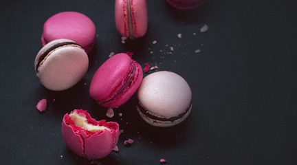 Macaroons on dark background, colorful french cookies macarons.Sweet dessert macaroon. The broken macarons with crumbs