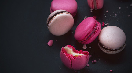 Macaroons on dark background, colorful french cookies macarons.Sweet dessert macaroon. The broken macarons with crumbs