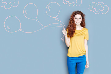 Holiday mood. Positive young babysitter getting ready for a Birthday party and holding beautiful balloons