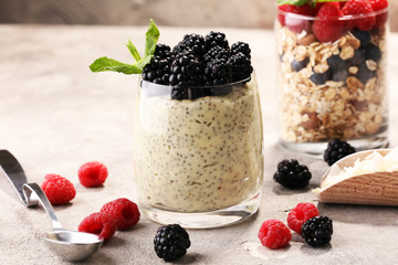 Healthy berry chia pudding in a jar with scattered fruit isolated on rustic grey background