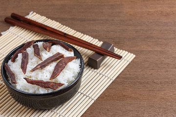 cooked jasmine rice topped with grilled sun dried beef in a ceramic bowl on wooden table, close up. homemade style food concept.