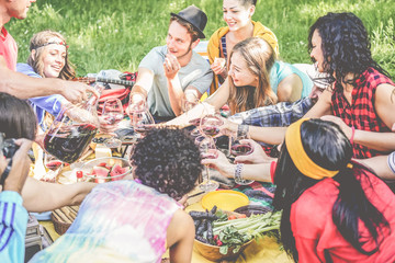 Group of happy friends enjoying picnic while drinking red wine and eating snack appetizers outdoor