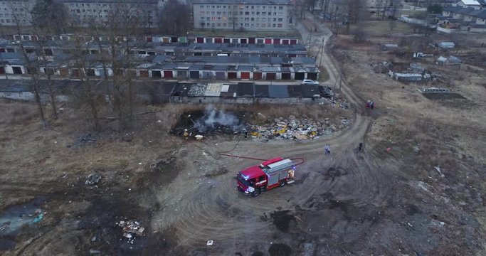 Aerial view of red fire truck with led light. Burning dump. Aerial view from drone of dense smoke poured in air and red fire-truck on fireground.
