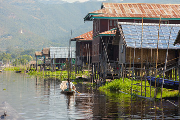 Inle Lake. Myanmar-December 21, 2015. Mine Thauk village houses on the water and woman rowing...