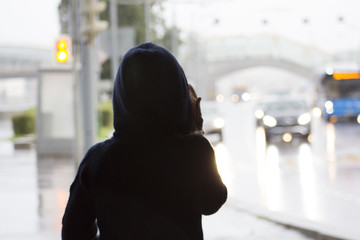 girl in a hoodie looks at the road with cars