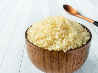 Parboiled rice groats in a wooden bowl on a light background