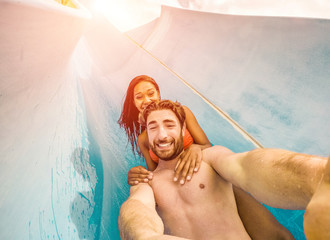 Happy crazy couple taking selfie photo with action camera in aqua park - obrazy, fototapety, plakaty