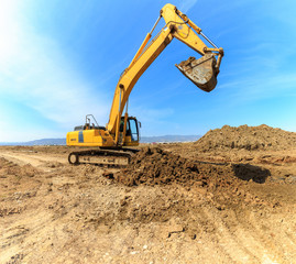Yellow excavator on a construction site over blue sky