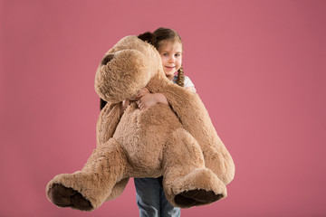 Happy young girl holding big teddy bear