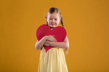 Young happy girl with closed eyes holding big red heart