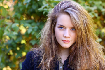 Close up portrait of young blonde beautiful woman in autumn park