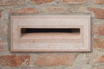 mail box in pink marble, on a  wall of briks
