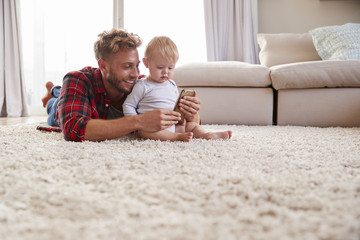 Young father taking selfie with toddler son in sitting room