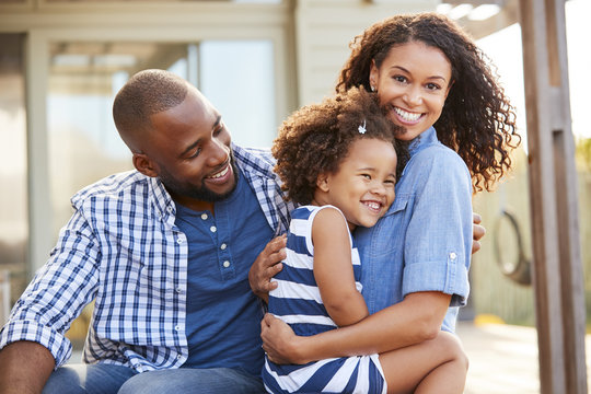 Black family embracing outdoors smiling to camera outside