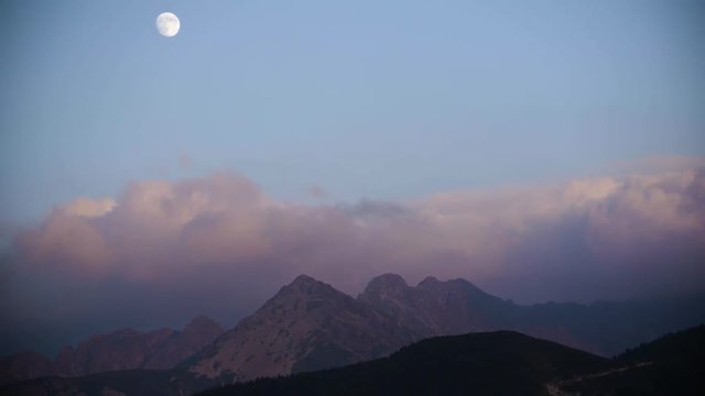 Timelaps of the mountains showing the passage of clouds and the moon in the sky during the day 4k HDR H264