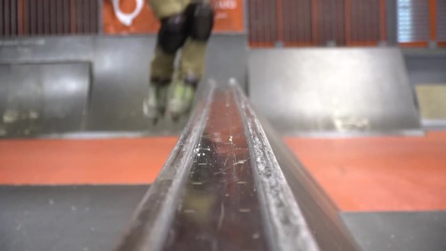 A man in an orange sweatshirt skates on roller skates in a skate park, slow motion.Niffty