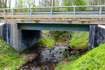 Automobile bridge with a fence through a stream
