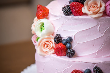 Three tiered pink wedding cake decorated with berries and flowers. Concept patisserie floristic from sugar mastic