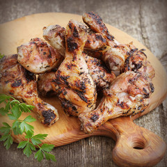 Grilled chicken legs on cutting board.Rustic dinner background