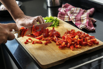 Chef chopping red pepper on a wooden board