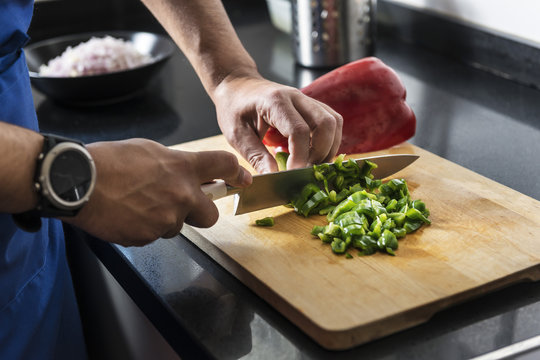 chef chopping green pepper on a cutting board