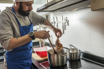 man with beard cooking chicken in the home kitchen