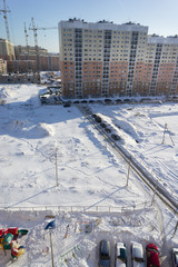 Obraz premium new high-rise building next to the snow-covered field under the blue sky and the sun.