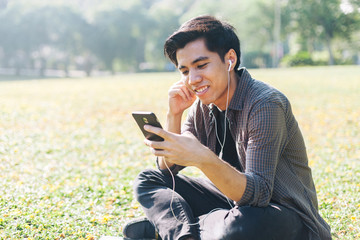 Fototapeta premium Young man selecting and listen to music using his device
