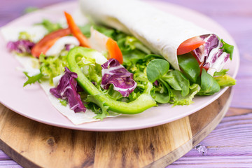 Fresh salad of greens in pita bread on a wooden background  for healthy lifestyle concept.