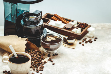 Variety things for prepare coffee. Roasted beans, ground coffee, scoop, electric coffee machine and assortment of sweets and spices to eat with on light background.