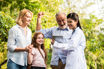 Doctor with family patients talking about medical consultation in a park. Healthcare concept