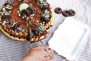 Homemade cake three chocolates with hand puting slice to plate. Mousse glaze darkness decoration cake.