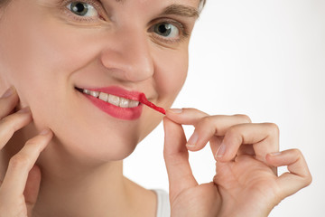 A beautiful young girl applies a persistent liquid red lipstick from a tube to her lips, and then takes it off as a film