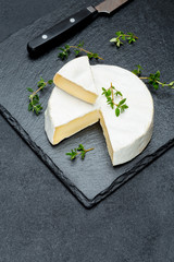 Obraz na płótnie Canvas Camembert cheese and cut a slice on stone serving board