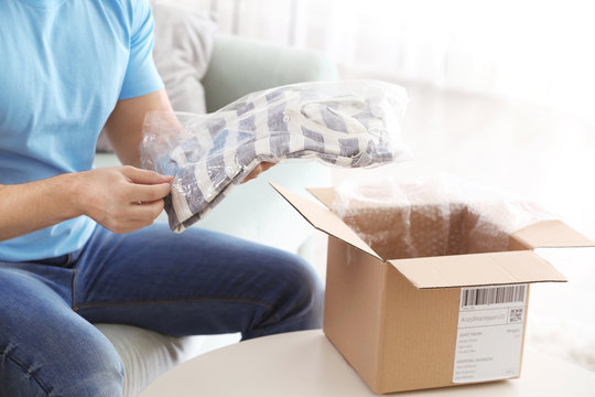 Young Man Unpacking Parcel At Home