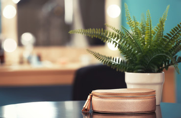 Cosmetic bag and plant on table in makeup room