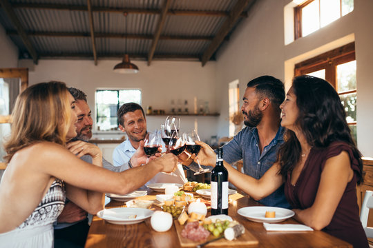 Cheerful friends toasting wine at dinner party