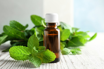 Bottle of essential oil with mint leaves on wooden table © New Africa