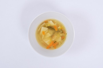 Noodle soup with vegetables on a white