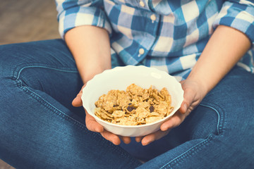 The girl is holding a plate of cereal with fruit. Healthy eating concept. Proper nutrition. Healthy food. Toned image.