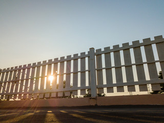 the sunset sky behind of the fence on the roof top.